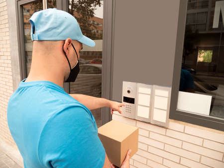 Caucasian man in uniform of postman or courier delivery man or parcels entering door and streetsの写真素材