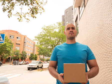 Caucasian man in uniform of postman or courier delivery man or parcels entering door and streetsの写真素材