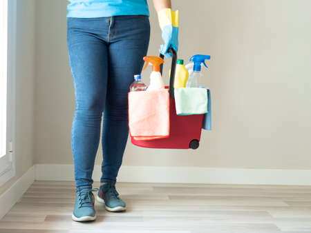Caucasian young woman cleaning with a bottle of water brush and broom her house with cleaning gloves and handkerchiefsの写真素材
