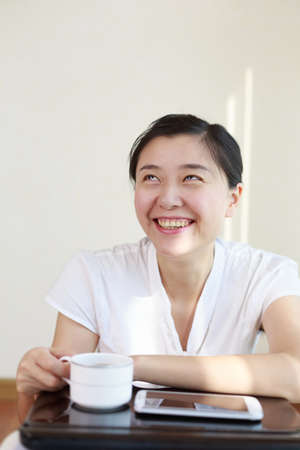 An Asian woman in a white shirt is laughing.の写真素材