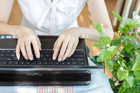 A pair of women's hands are tapping the keyboard
