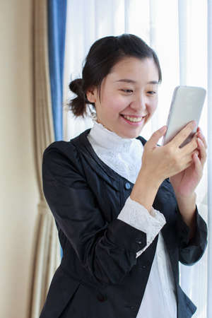 A professional woman smiling while looking at her phoneの写真素材