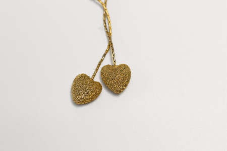 Two golden heart-shaped pendant on white backgroundの写真素材
