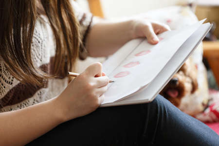 A girl writes with a pencil in her handの写真素材