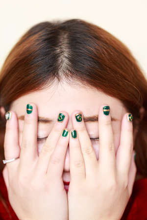A painted Nail Polish girl covered her face with her hands,