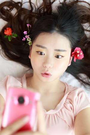 An Asian girl with a pink mobile phoneの写真素材