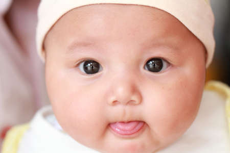 One year old baby looking at the lens with tongue out