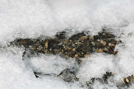 Ice lines the stream flowingの写真素材