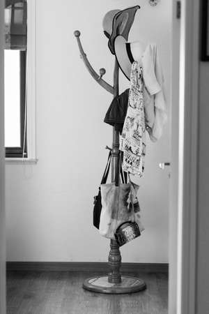 A coat rack with clothes and bags in the room