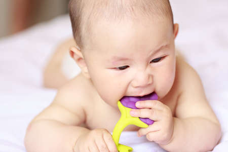 A baby is lying on a white sheetの写真素材