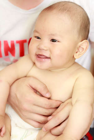 A baby was laughing happily in his father's arm