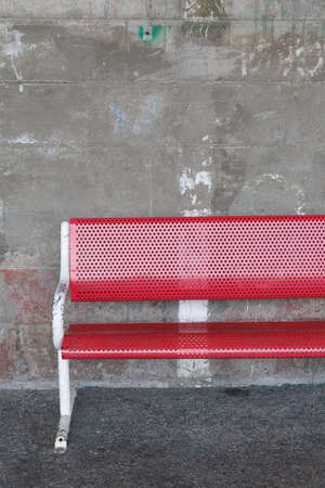 A red public seat is against the concrete wallの写真素材
