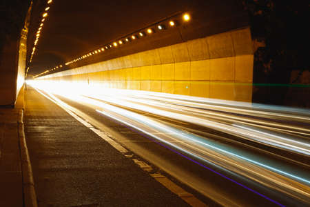 Cars leave a trail of light through the tunnel at nightの写真素材