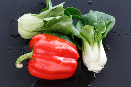 Two Chinese cabbage and a red pepper are on the black background.の写真素材