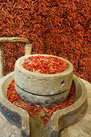 Red pepper is on the stone grinding millstone.の写真素材