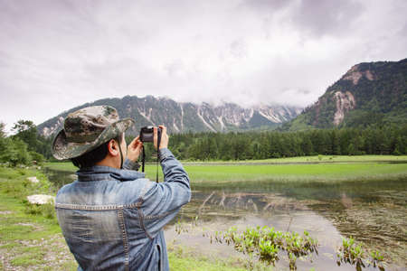 A man holds a camera to record plateau sceneryの写真素材