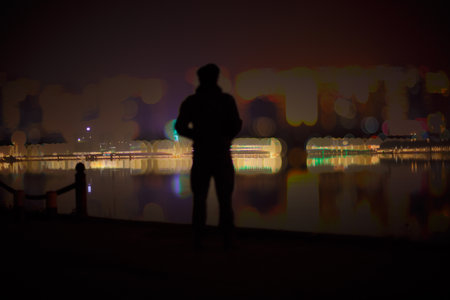 Silhouette of a man standing in front of the city at nightの写真素材