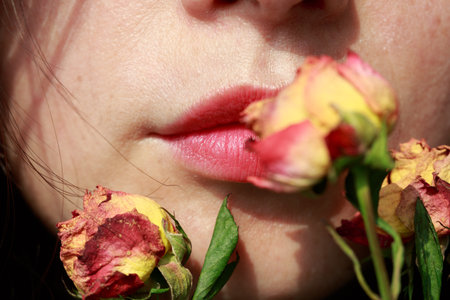 Close-up of a woman's lips with red lipstick and flowersの写真素材