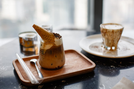 Iced coffee with ice cream in glass on wooden plate, selective focusの写真素材