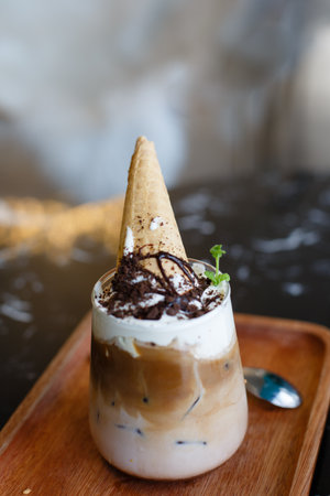 Ice coffee with whipped cream and chocolate in a glass on wooden tableの写真素材
