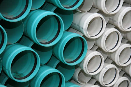 A horizontal image of green and white pvc pipes for underground services.