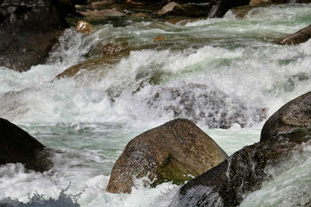 A mountain stream running at full capacity during spring runoff, and almost at flood stage.の写真素材