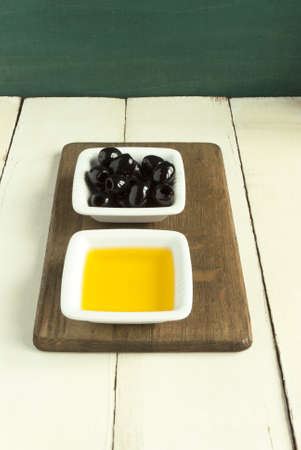 black olives and olive oil in white dishesの写真素材