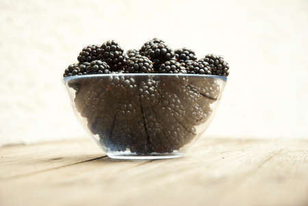 blackberries in bowl, on wooden tableの写真素材