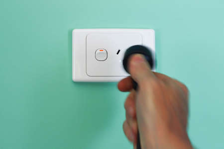 Power cord being removed from an Australian power socket.