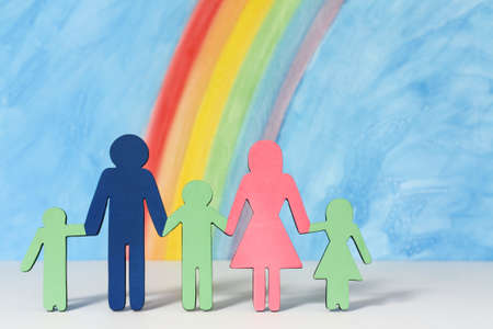 Father, mother and children icons with a rainbow and blue sky to illustrate the concept of the traditional family unit in portrait format.の写真素材