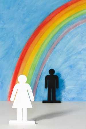 Man and women icons with a rainbow and blue sky to illustrate the concept of male, female and sexual discriminationの写真素材