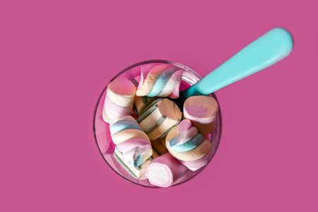 sweet marshmallows with blue spoon in a glass on a pink backgroundの写真素材