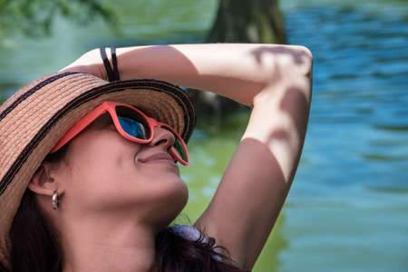 Young beautiful woman with a straw hat, resting in the park.の写真素材