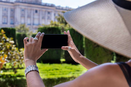 Beautiful young woman taking a photograph with the mobile in the park.の写真素材