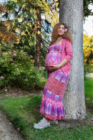 Beautiful pregnant woman smiling in the park in a sunny day. Maternity concept.の写真素材