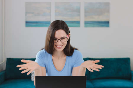 Attractive friendly woman sitting at desk with laptop wearing headphones talking with customers...