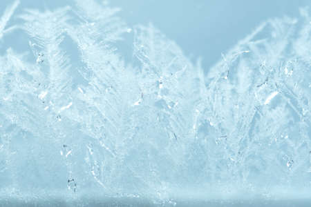 Closeup winter window pane coated shiny icy frosted patterns. Abstract beautiful ice flowers...