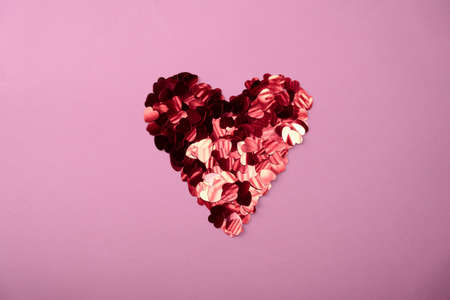 Rose color festive background with red heart shaped bunch of confetti. Flatlay style with copy space for text, design Trendy Valentine's concept. Perfect pink backdrop for social media, blog, postcardの写真素材