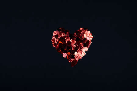 Black color festive background with red heart shaped bunch of confetti. Flatlay style with copy space for text design Trendy Valentines concept. Perfect pink backdrop for social media, blog, postcardの写真素材