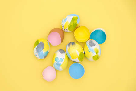 Top view of easter holiday yellow backdrop with creative eggs decorations in trendy blue, gray,...