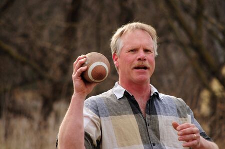 senior caucasian male throwing footballの写真素材