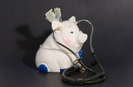 piggy bank holding a stethoscope to pigs heartの写真素材