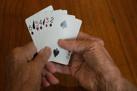 elderly hands holding a bad losing hand of playing cardsの写真素材