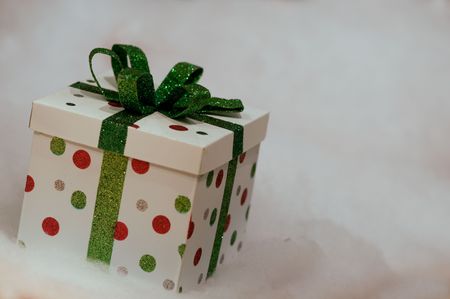 Small polka dot gift with green ribbon on a snow backgroundの写真素材