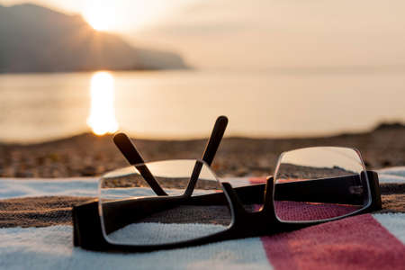 glasses and beach towel in sunsetの写真素材