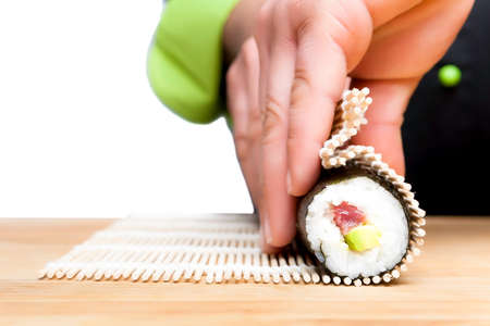 closeup of chef hands rolling up sushi - focus on the rollの写真素材