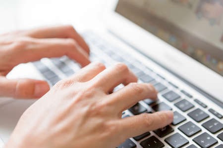closeup of female hands typing on laptop keyboard - focus on a right hand - focus on the idex...