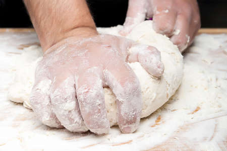 closeup of hands kneading bread on a wooden board - focus on the index fingerの写真素材