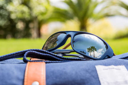 reflection of palms beach on polarized sunglasses over a travel backpack - focus on the right lense - travel conceptの写真素材