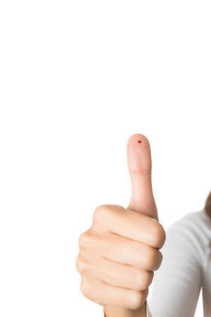 closeup of a thumb up with drop of blood isolated on a white background - focus on the drop of blood and thumbの写真素材